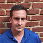 Man standing in front of a brick wall
