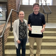 Two people smiling on stairs, one holding a certificate
