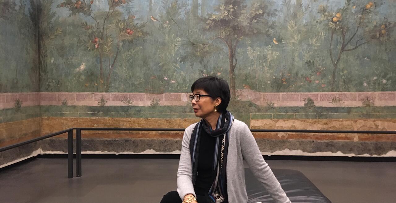 Deborah Parker sitting on a bench in a room with painted walls